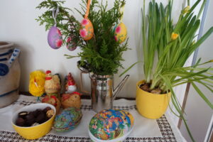 Bord med gule påskeblomster, påskepynt med kyllinger og påskeegg med godteri